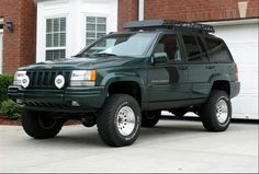 a green jeep parked in front of a house