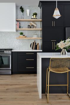 a modern kitchen with black cabinets and white counter tops, gold chairs and brass accents