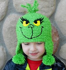 a young boy wearing a green crocheted hat with an angry grin face on it