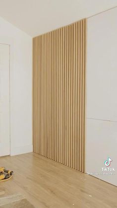 a room with hard wood flooring and white walls that have vertical slats on them