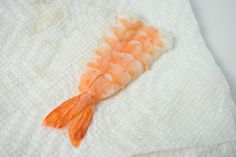 an orange shrimp is laying on a white towel