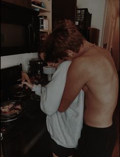 a shirtless man is cooking in the kitchen while looking at something on the stove