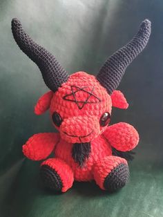 a crocheted red and black stuffed animal with horns