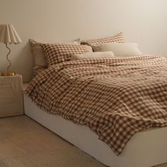 a bed with brown and white checkered comforter on top of it next to a night stand