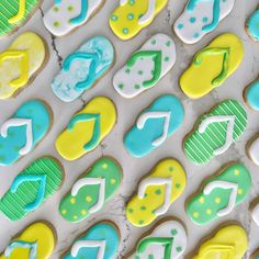 many decorated cookies are arranged on a marble counter top, with blue and yellow icing in the shape of musical notes