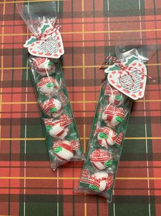 two packages of christmas candies on a plaid tablecloth with tags attached to them