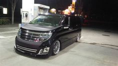 a black van parked in front of a gas station at night with its lights on