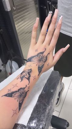 a woman's hand with butterfly tattoos on her left arm and the other hand