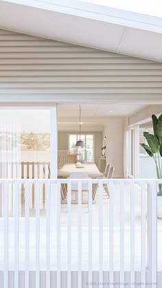 an open door leading to a dining room and living room with white furniture in the background