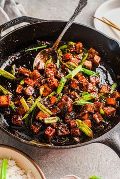 a skillet filled with tofu and asparagus on top of white rice