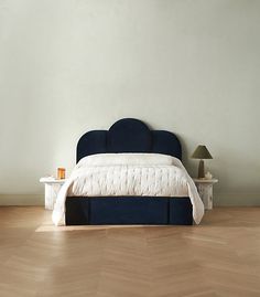 a bed sitting on top of a hard wood floor next to a night stand and lamp