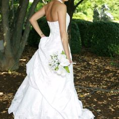 a woman in a wedding dress standing under a tree