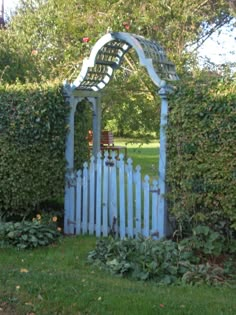 a white gate in the middle of some bushes