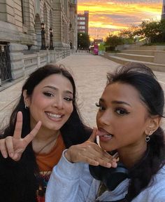 two women posing for the camera with their fingers in the air and one pointing up