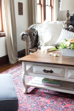 a living room with a couch, coffee table and rug on the floor in front of it