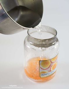 a glass jar filled with liquid sitting on top of a white table next to a metal cup