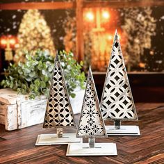 three metal christmas trees sitting on top of a wooden table