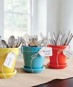 four pots with forks and spoons in them sitting on a table next to each other