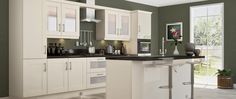 a large kitchen with white cabinets and black counter tops in front of a green wall