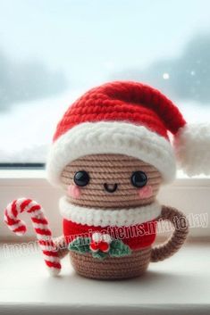 a small stuffed animal wearing a santa hat and holding a candy cane on a window sill