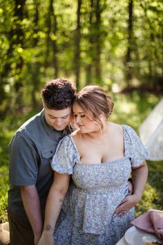 a man and woman standing next to each other in the woods