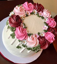 a white cake with pink and red flowers on it