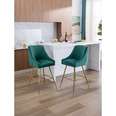 two green chairs sitting on top of a wooden floor next to a white countertop