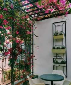 an outdoor table and chairs with flowers growing on the wall