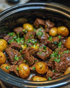 beef and potatoes in a crock pot with parsley on top, ready to be eaten