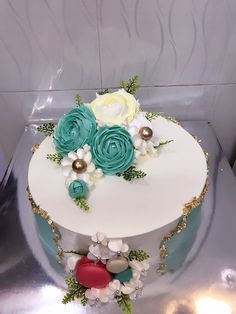 there is a white cake with blue flowers on top and gold trim around the edges