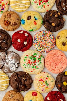 many different types of cookies on a white surface with icing and sprinkles