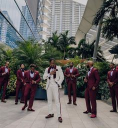 a man standing in front of a group of men wearing red and white suit jackets