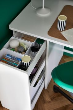 an office desk with two cups on it and some other items in the drawer underneath