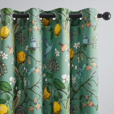 a green curtain with yellow flowers and birds on it, hanging from the side of a window