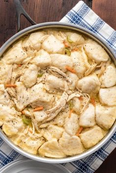 a pot filled with chicken and dumplings on top of a wooden table