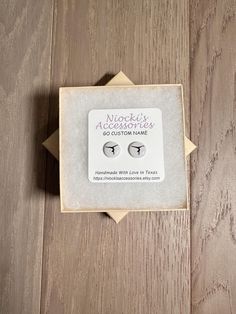 a pair of earrings sitting on top of a wooden table next to a card with the word nuggie's accessories written on it