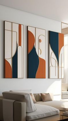 three abstract paintings hang on the wall above a couch in a living room with white walls