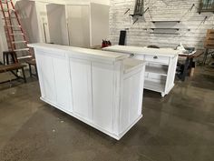 a white kitchen island in a room with brick walls and flooring, surrounded by tools