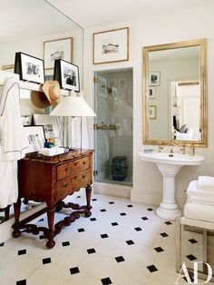 a white bathroom with black and white flooring and pictures on the wall above it