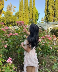 a woman in a pink dress picking flowers