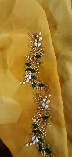 a close up view of a yellow fabric with green and white flowers on the side