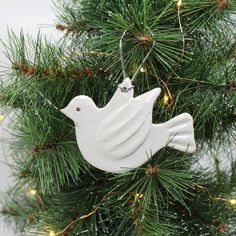 a white bird ornament hanging from a christmas tree