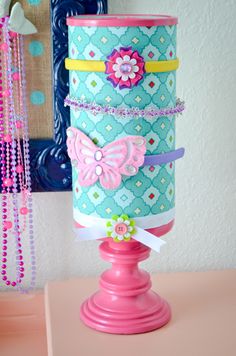 a pink candle holder sitting on top of a table next to beads and necklaces