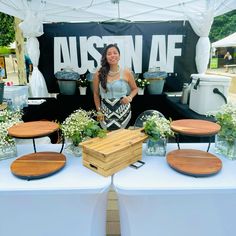 a woman standing in front of a table with wooden cutting boards on top of it