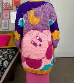 a woman is wearing a crocheted sweater with peppa pig on the back