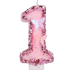 a pink number one shaped candle with butterflies on it's top and the number 1 in the middle