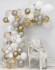 white and gold balloons are arranged in the shape of an arch, with a chair next to it