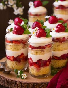 strawberry shortcakes with whipped cream and fresh strawberries in small jars on a wooden tray