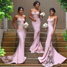 three beautiful women in pink dresses standing on steps with bouquets and greenery behind them