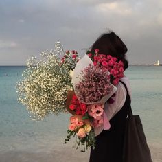 a woman holding flowers in front of the ocean with a quote from cocolo on it